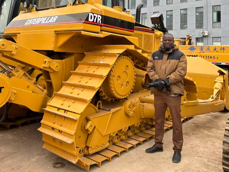 Global client standing next to an inspected used CAT crawler bulldozer ready for shipping