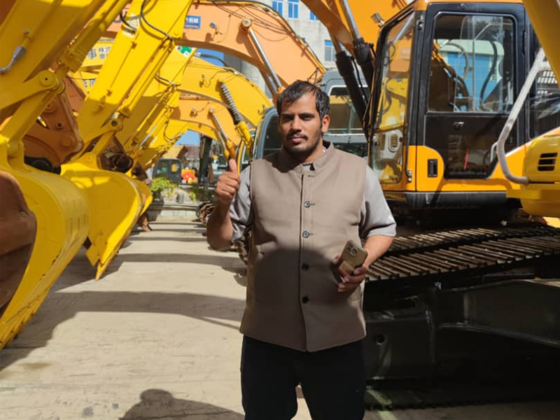 International buyer posing with Komatsu and CAT excavators row at our heavy machinery yard